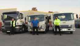 three metelec employees standing in front of delivery trucks